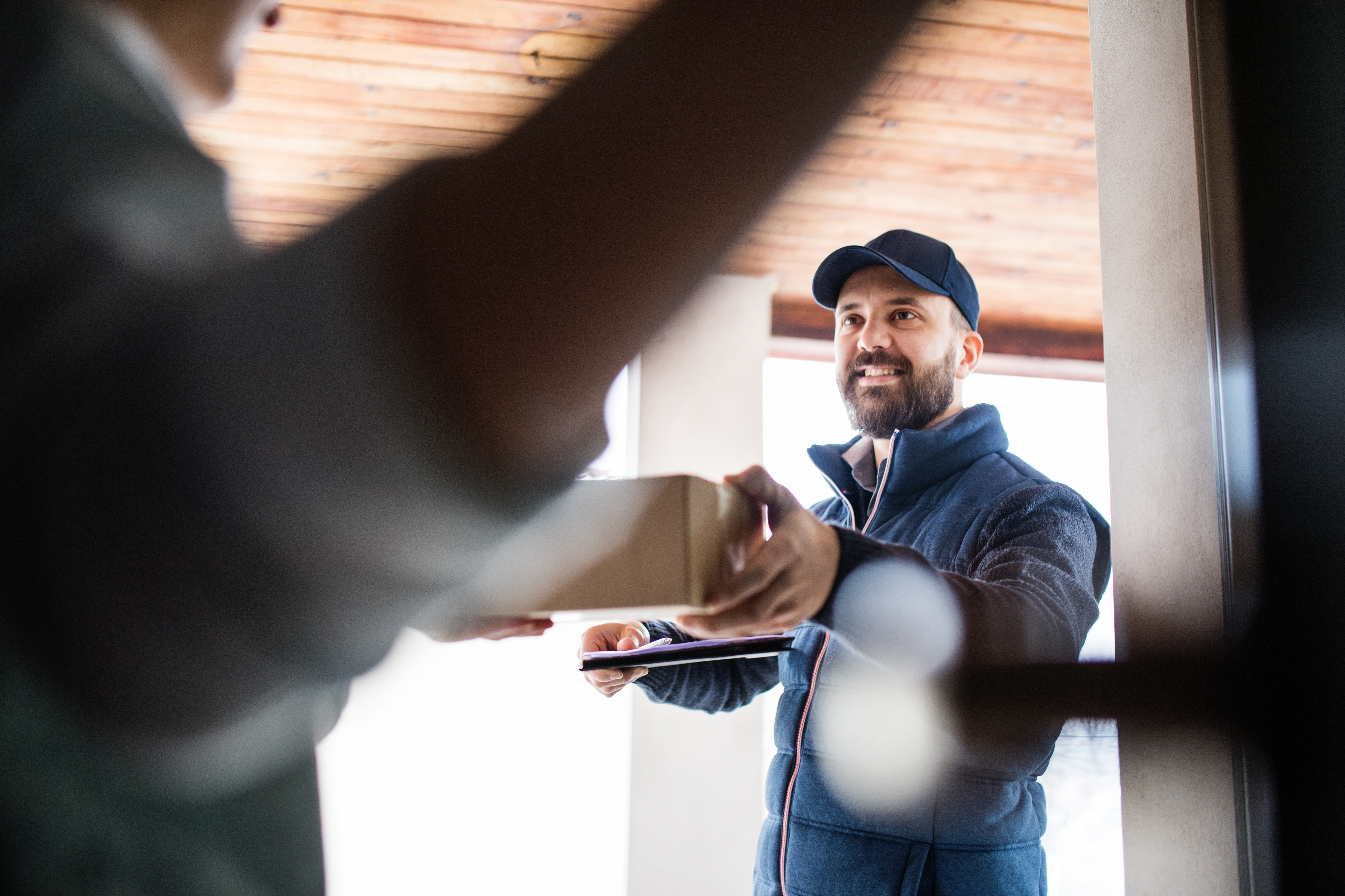 Delivery driver handing a package to a customer at their door